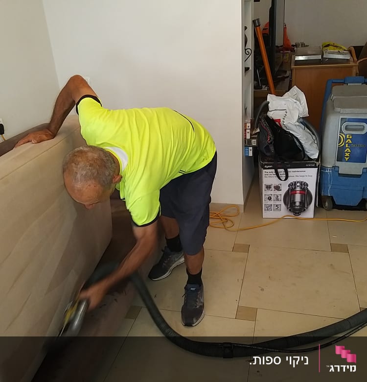 אדם מנקה ספה עם מכשיר שאיבה